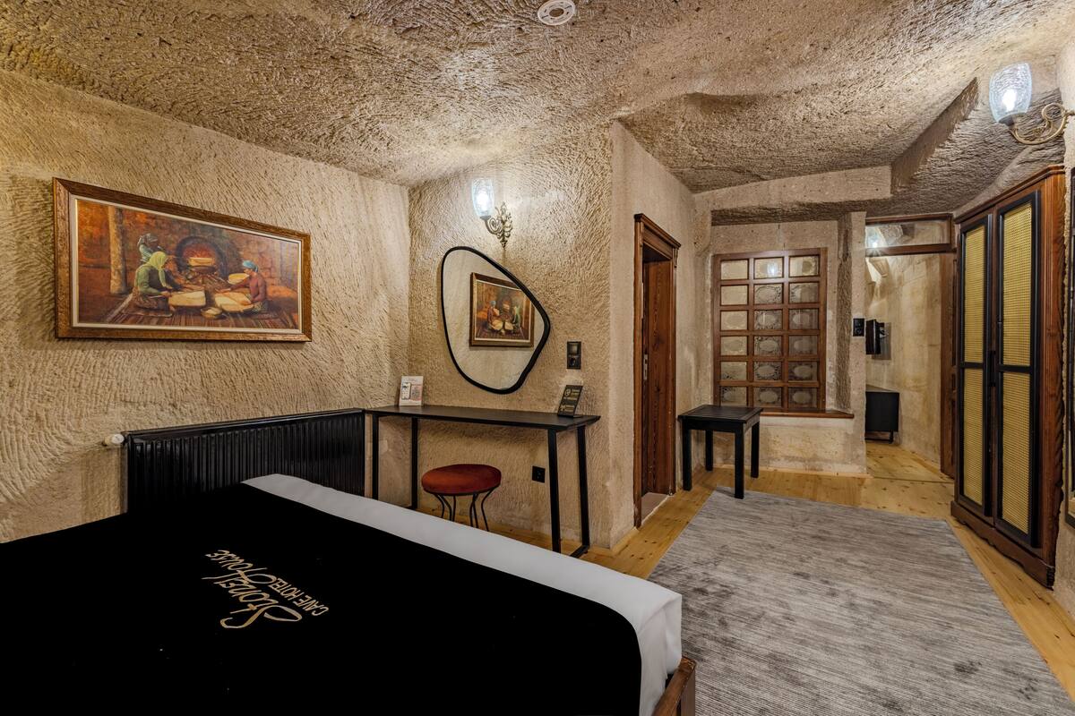 Ein Zimmer mit einem Bett, einem Schreibtisch, einem Stuhl, einem Gemälde und einer Tür.