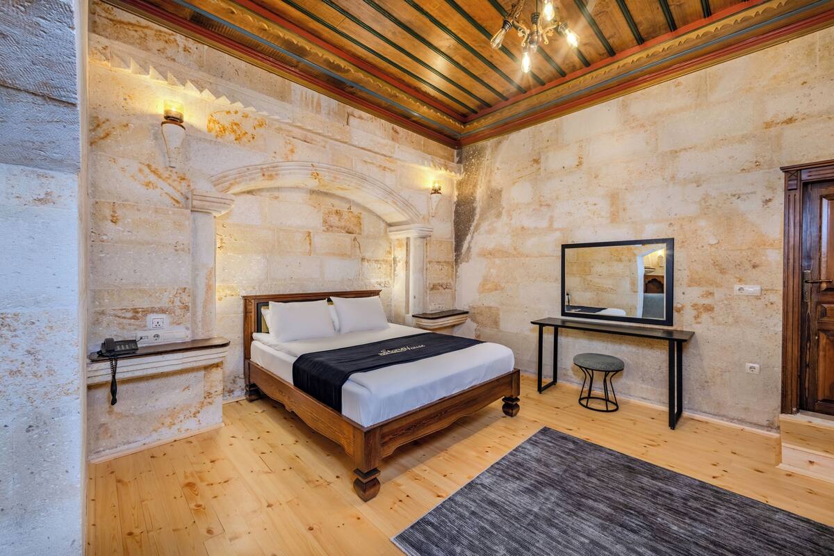 Ein Schlafzimmer mit einem hölzernen Bett, einem Nachttisch, einem Spiegel und einem kleinen Tisch.