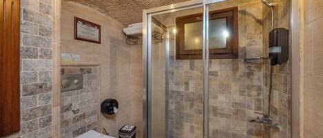 A bathroom with a shower, toilet, and a wall-mounted towel dispenser.