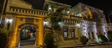 A historic building with an ornate entrance, a sign indicating it is a restaurant, and a balcony with potted plants.