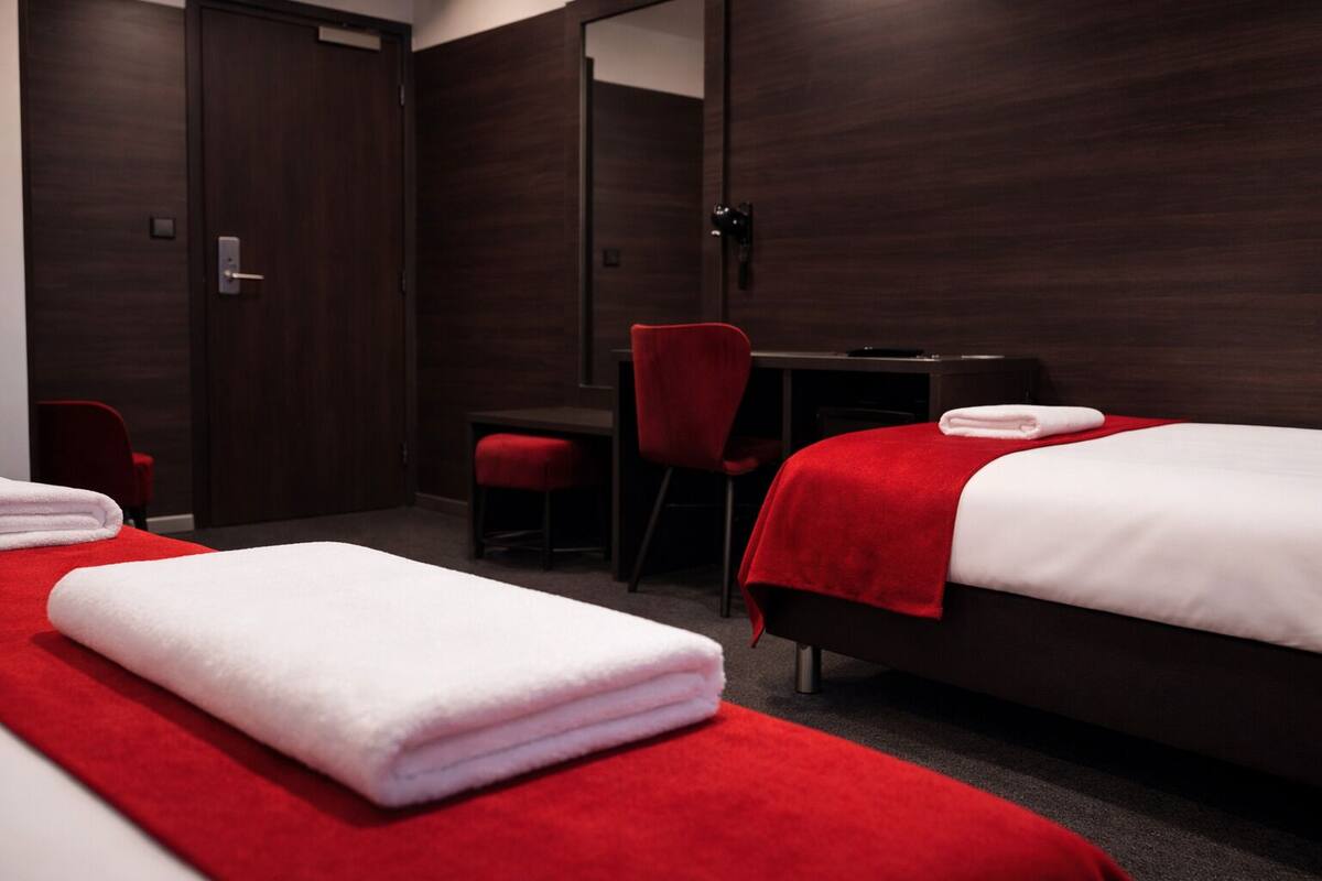 Une chambre d’hôtel avec deux lits, un bureau et une chaise.