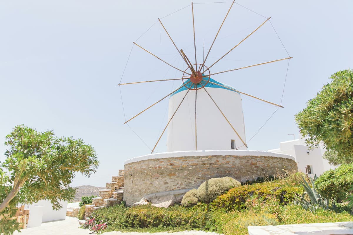 Eine Windmühle mit weiß-blauer Struktur, umgeben von Grünflächen und Steintreppen.