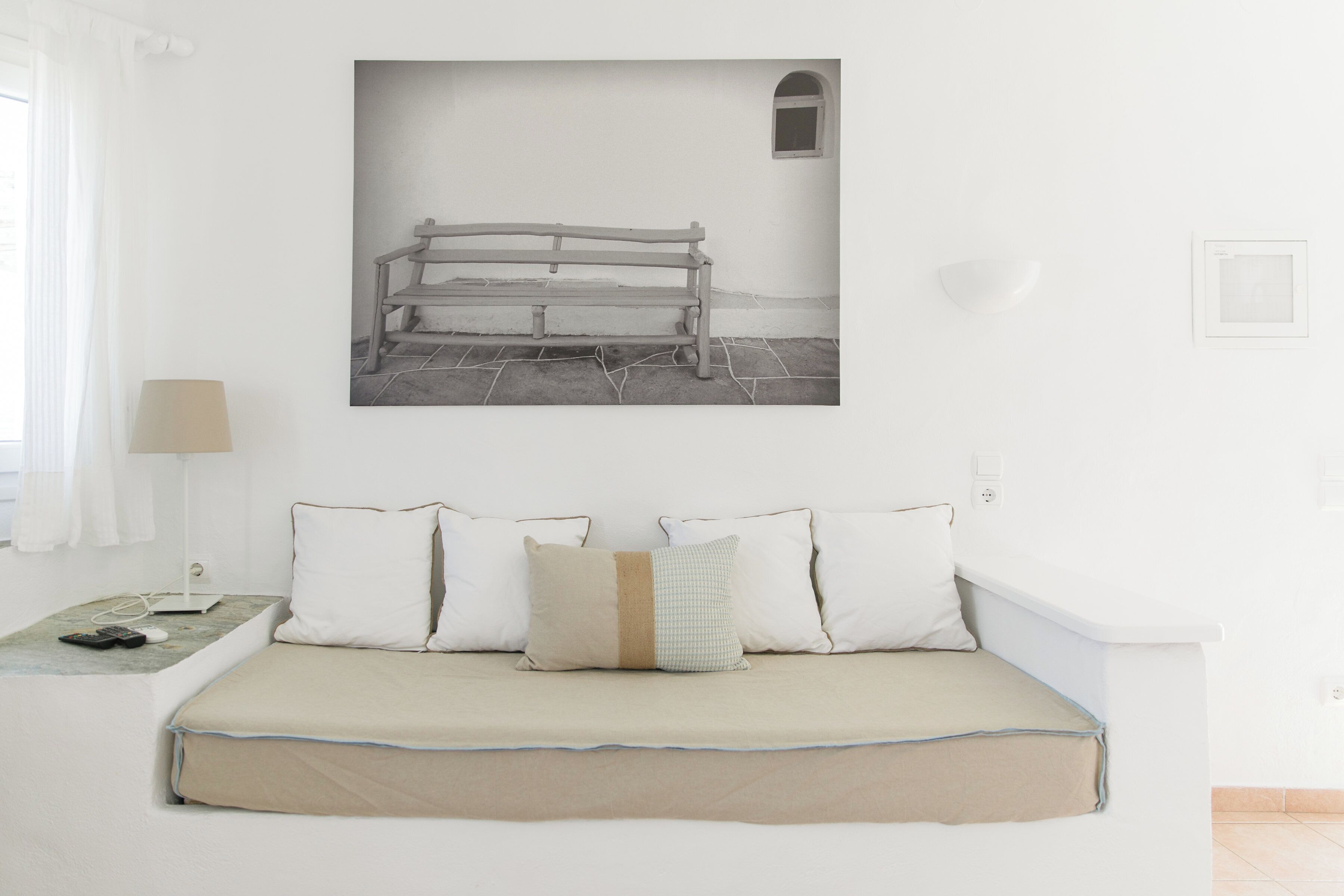 A minimalist bedroom with a bed, a bedside table, a lamp, and a wall-mounted picture.