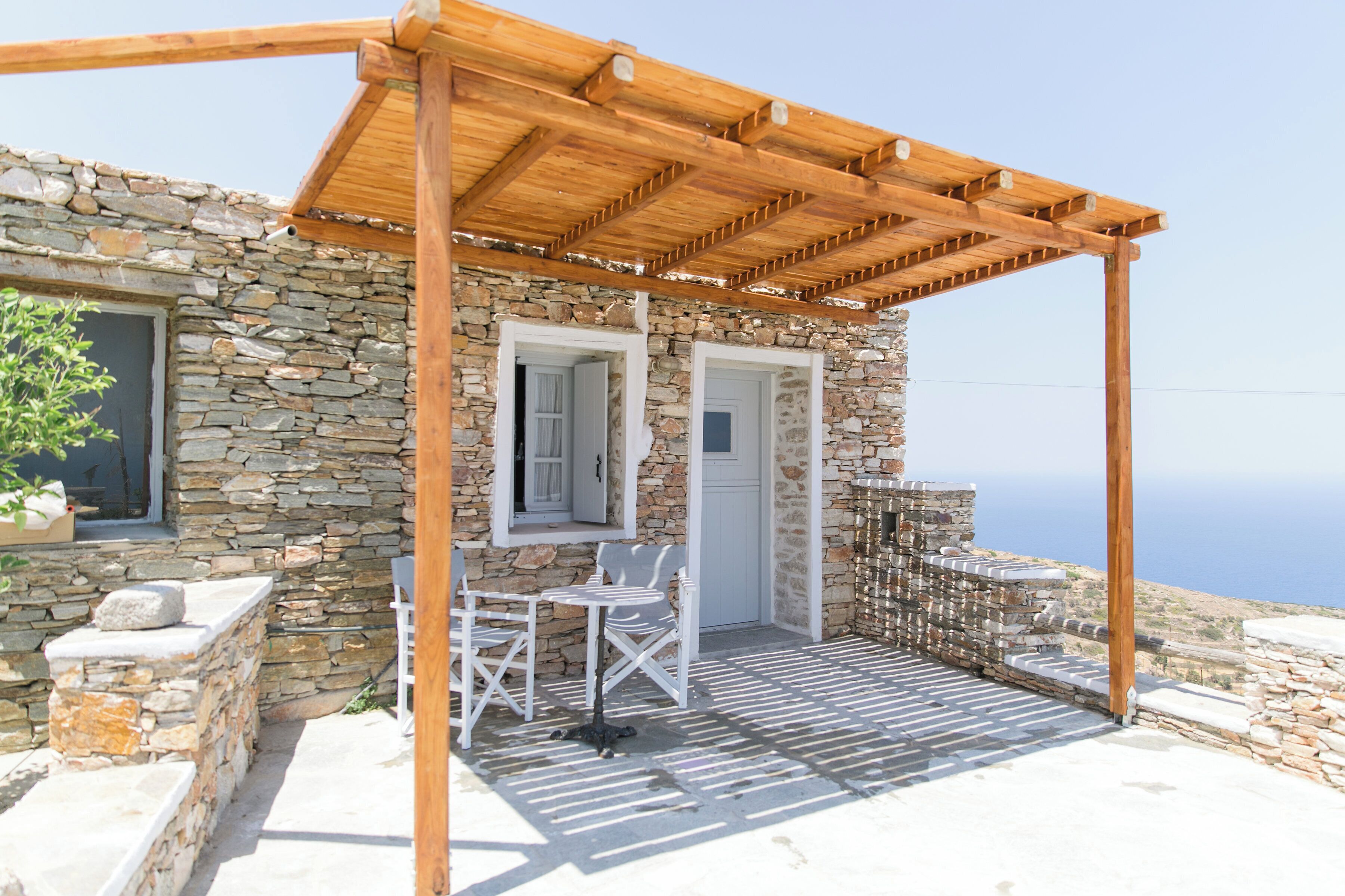 A stone building with a wooden pergola and outdoor seating.