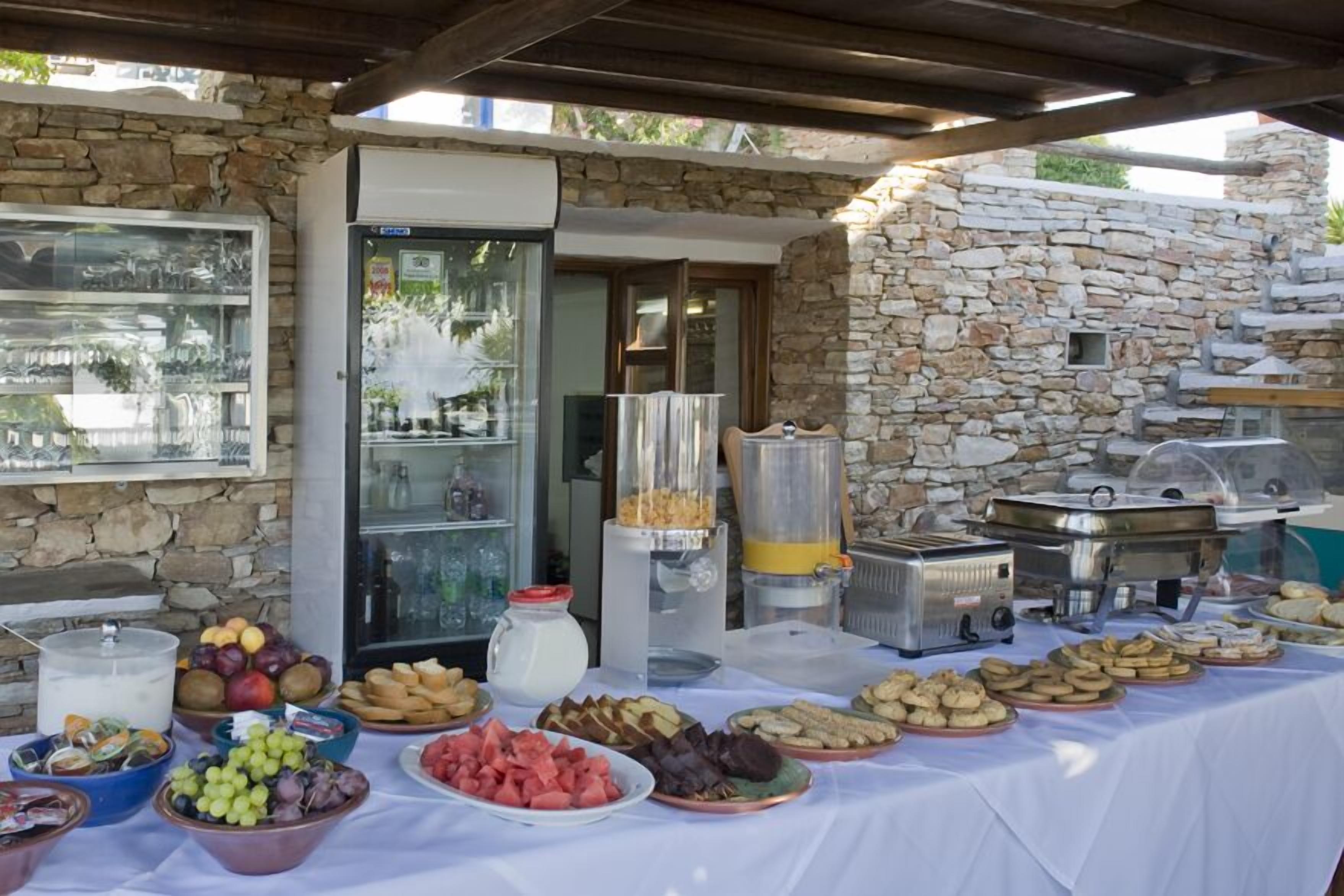 Een buffetopstelling met diverse gerechten en een drankstation, met een stenen muur op de achtergrond.