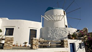Un bâtiment traditionnel de couleur blanche, avec une porte bleue et un moulin à vent.