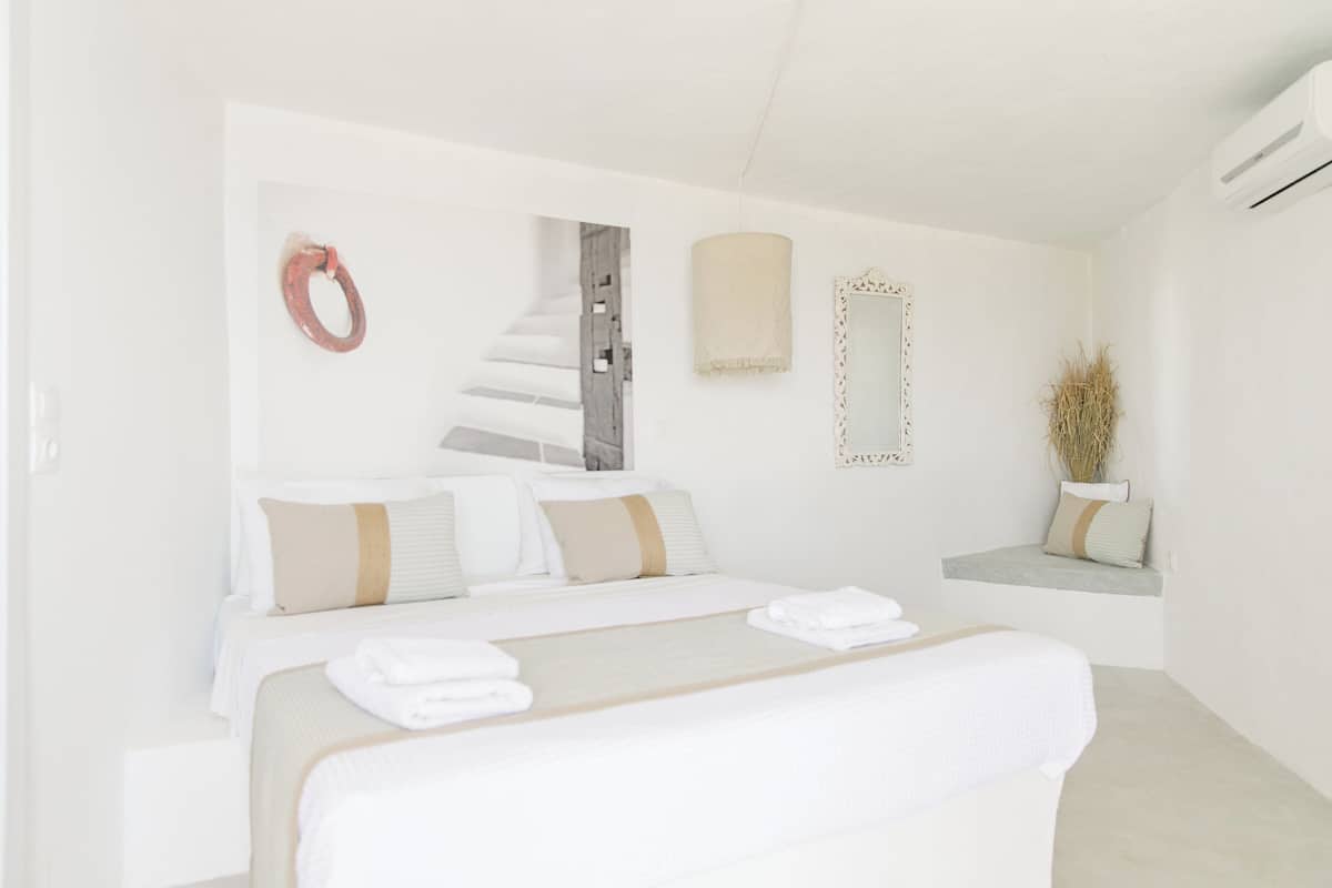 Ein Schlafzimmer mit einem Bett, einem Spiegel, einer runden Wanddekoration und einem kleinen Regal mit einer Pflanze.