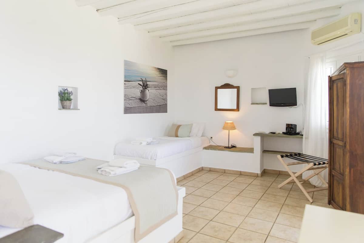 Ein Hotelzimmer mit Bett, Schreibtisch, Fernseher und Kleiderschrank.
