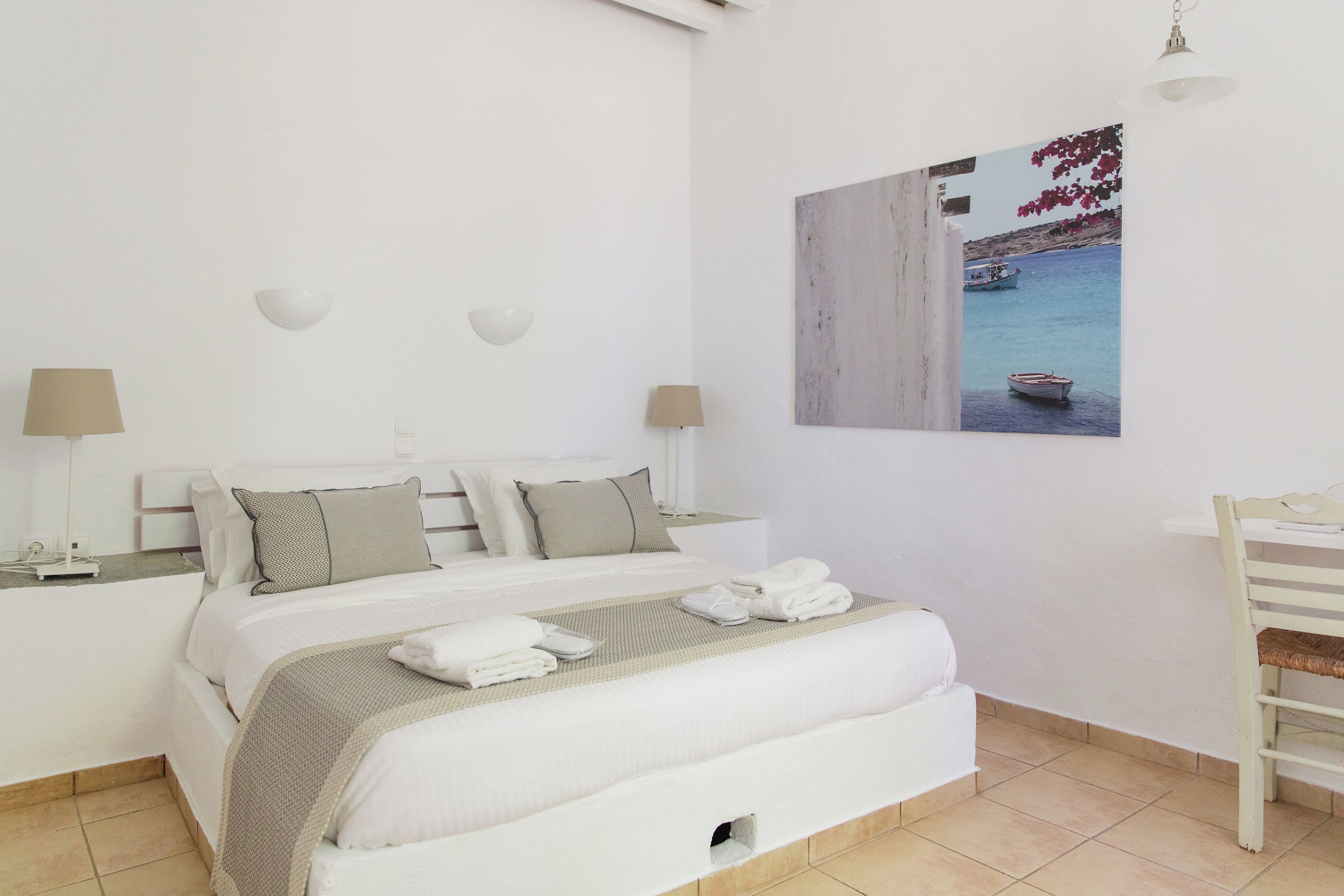 A neatly arranged bedroom with a bed, bedside tables, and a wall-mounted picture.