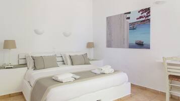 A neatly arranged bedroom with a bed, bedside tables, and a wall-mounted picture.