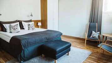 Habitació d'hotel moderna amb un llit gran, un armari de fusta, un escriptori i una cadira.