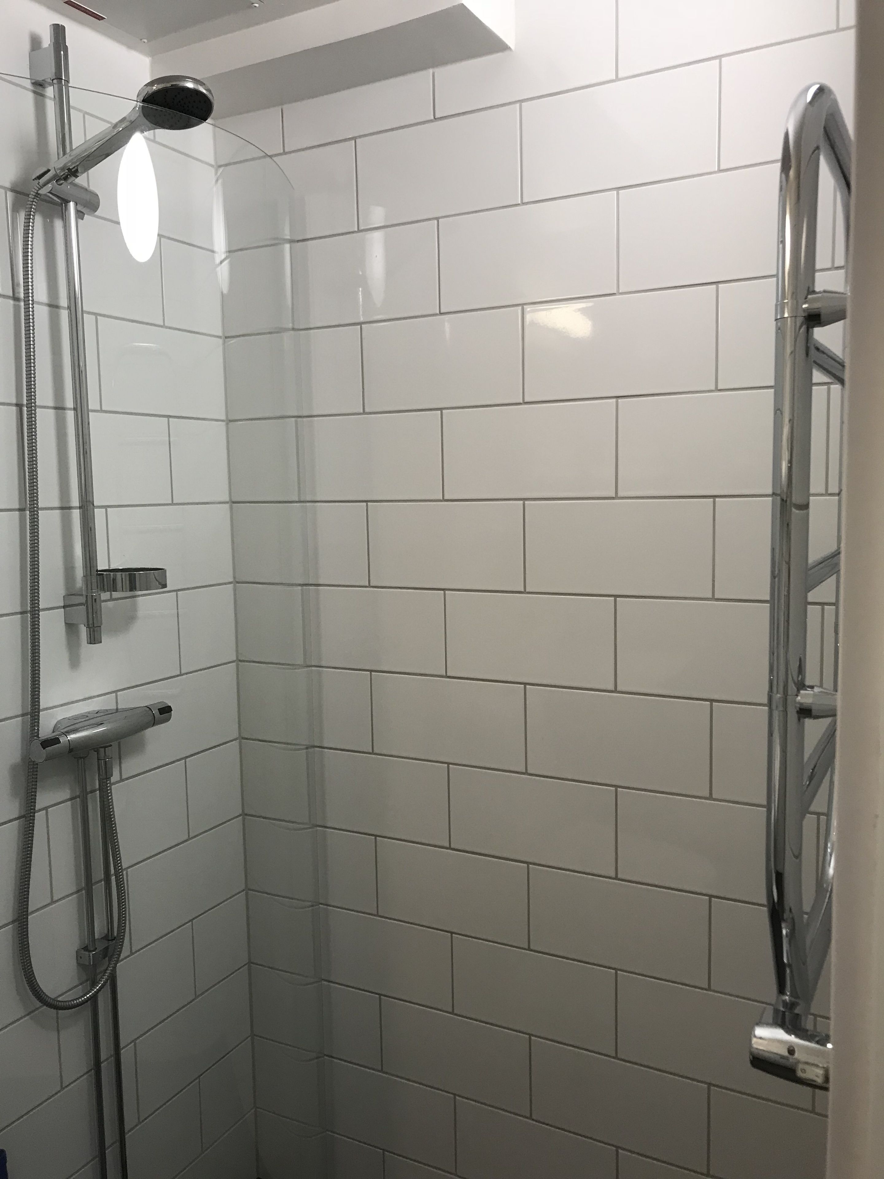 A shower with a handheld showerhead and a handheld shower attachment.