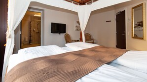 Habitación de hotel con una cama grande, un televisor montado en la pared y un área de ducha visible a través de una puerta abierta.