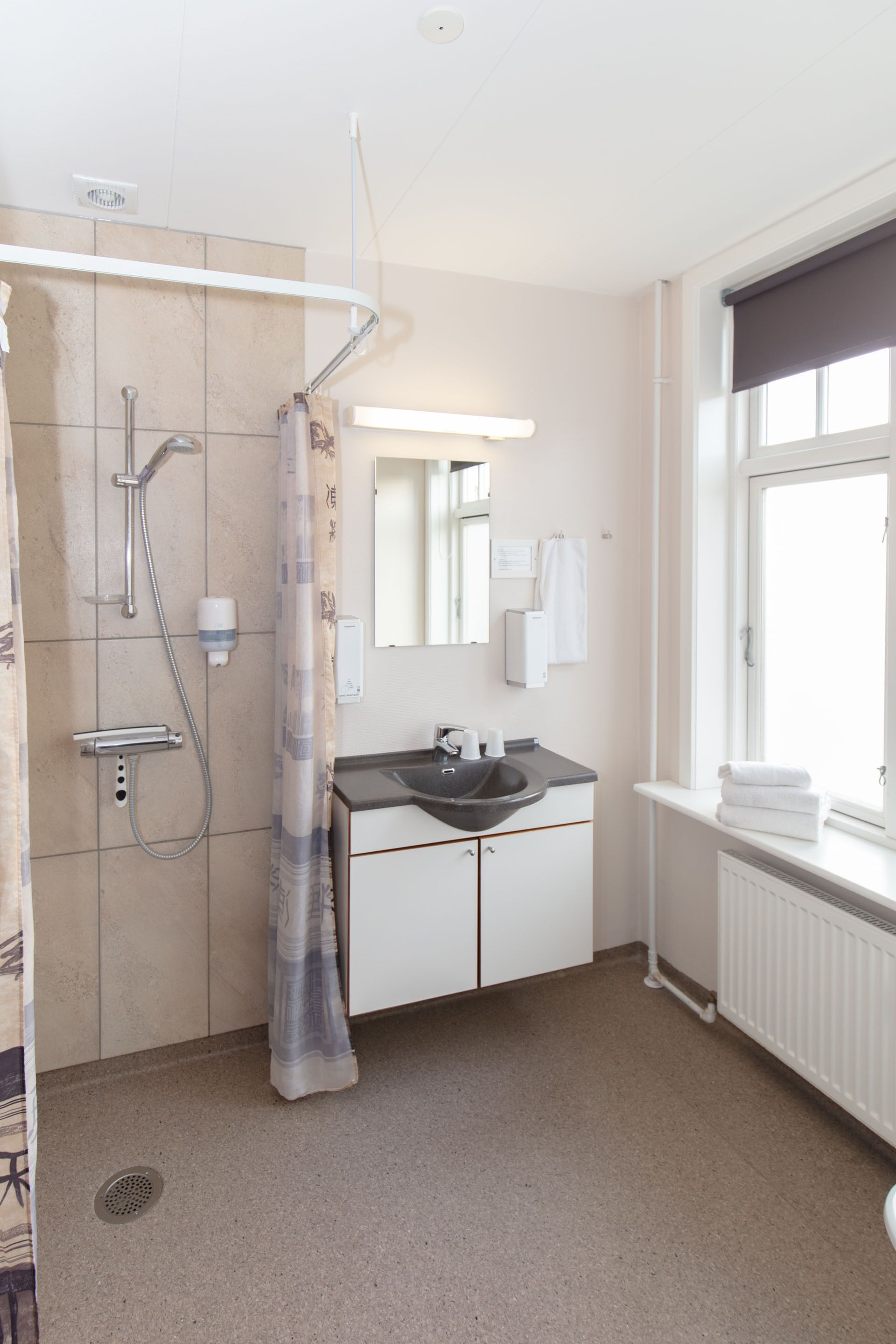 A bathroom with a shower, sink, and window.
