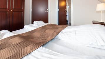A hotel room with a bed, a wooden wardrobe, and a door leading to another room.