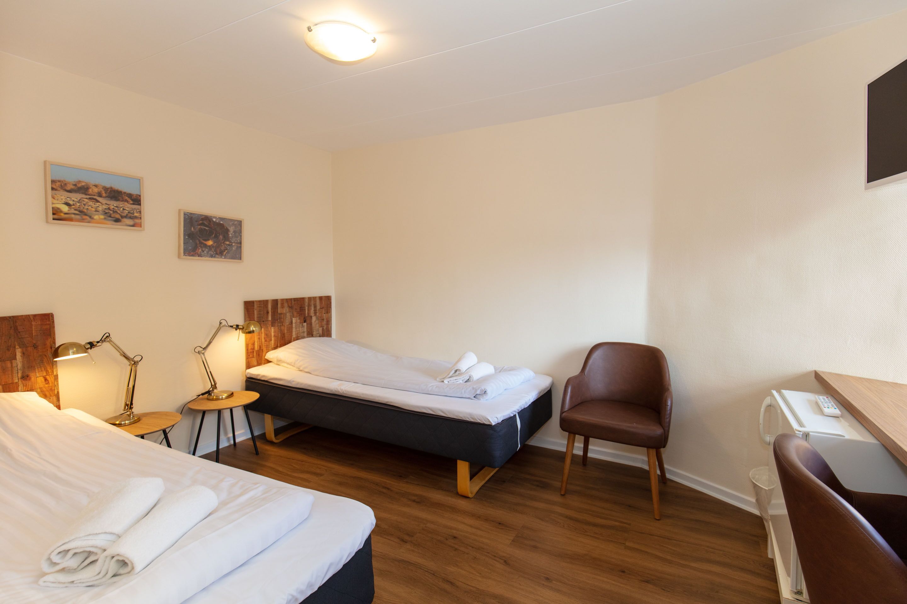 A hotel room with two beds, a desk, a chair, and two bedside lamps.