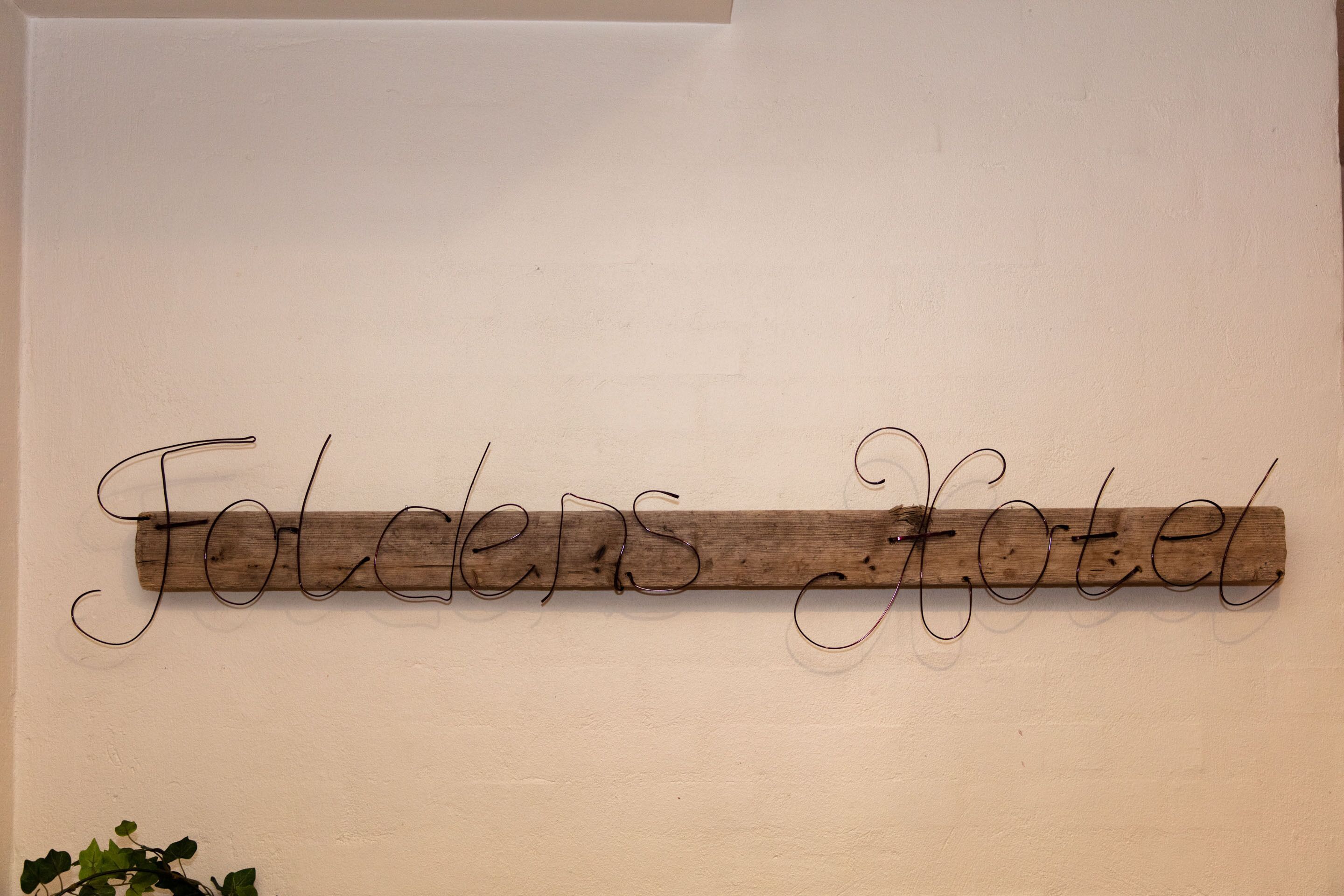 A wooden sign with the text "Folders Hotel" mounted on a wall.