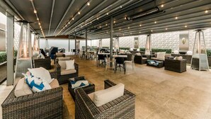 An outdoor lounge area with wicker furniture, tables, and chairs. - The Place (Edinburgh)