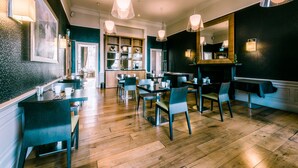 A restaurant with wooden flooring, tables, chairs, and pendant lighting. - The Place (Edinburgh)
