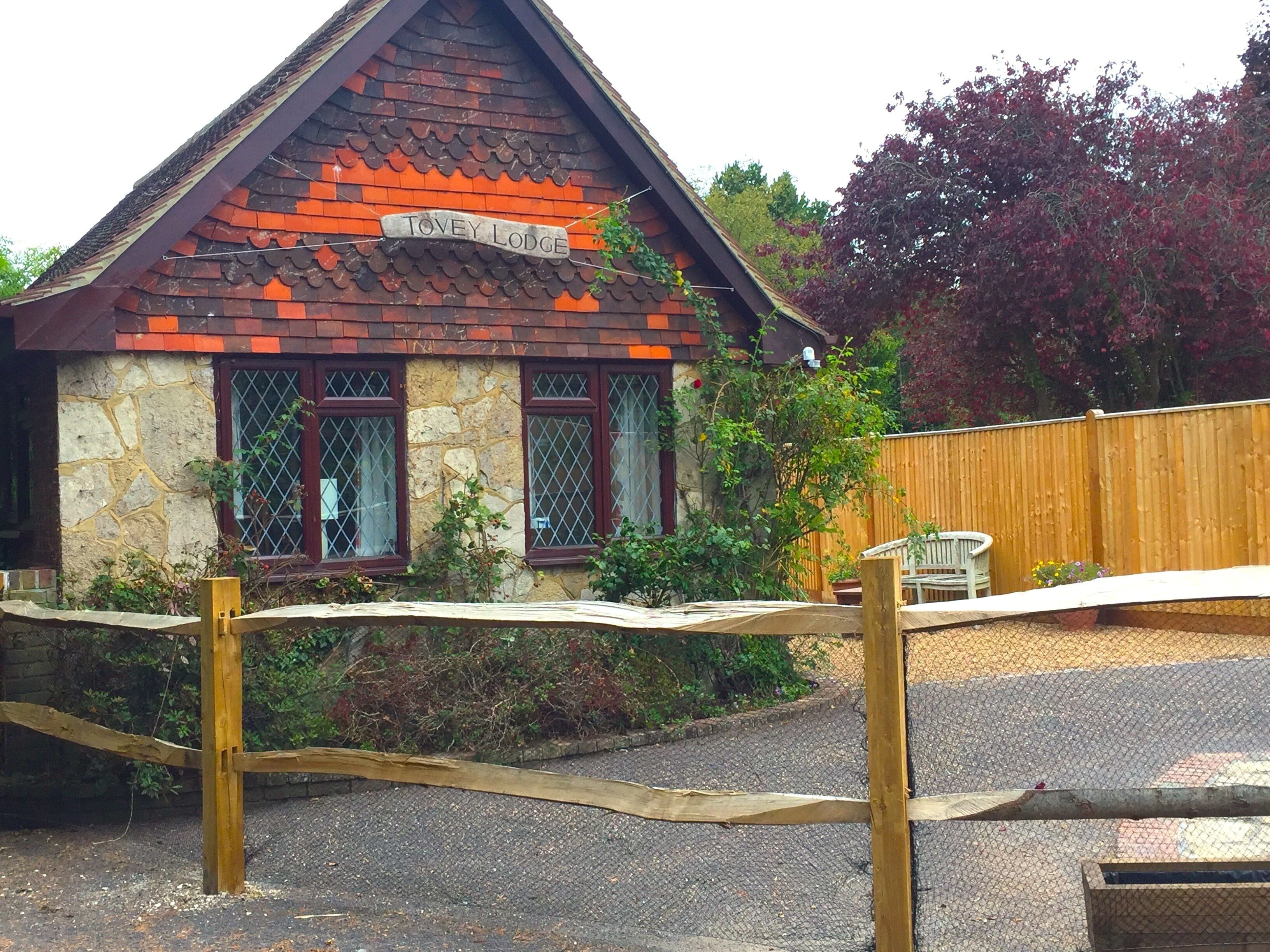A lodge with a stone facade, a wooden fence, and a sign reading "Tovey Lodge".