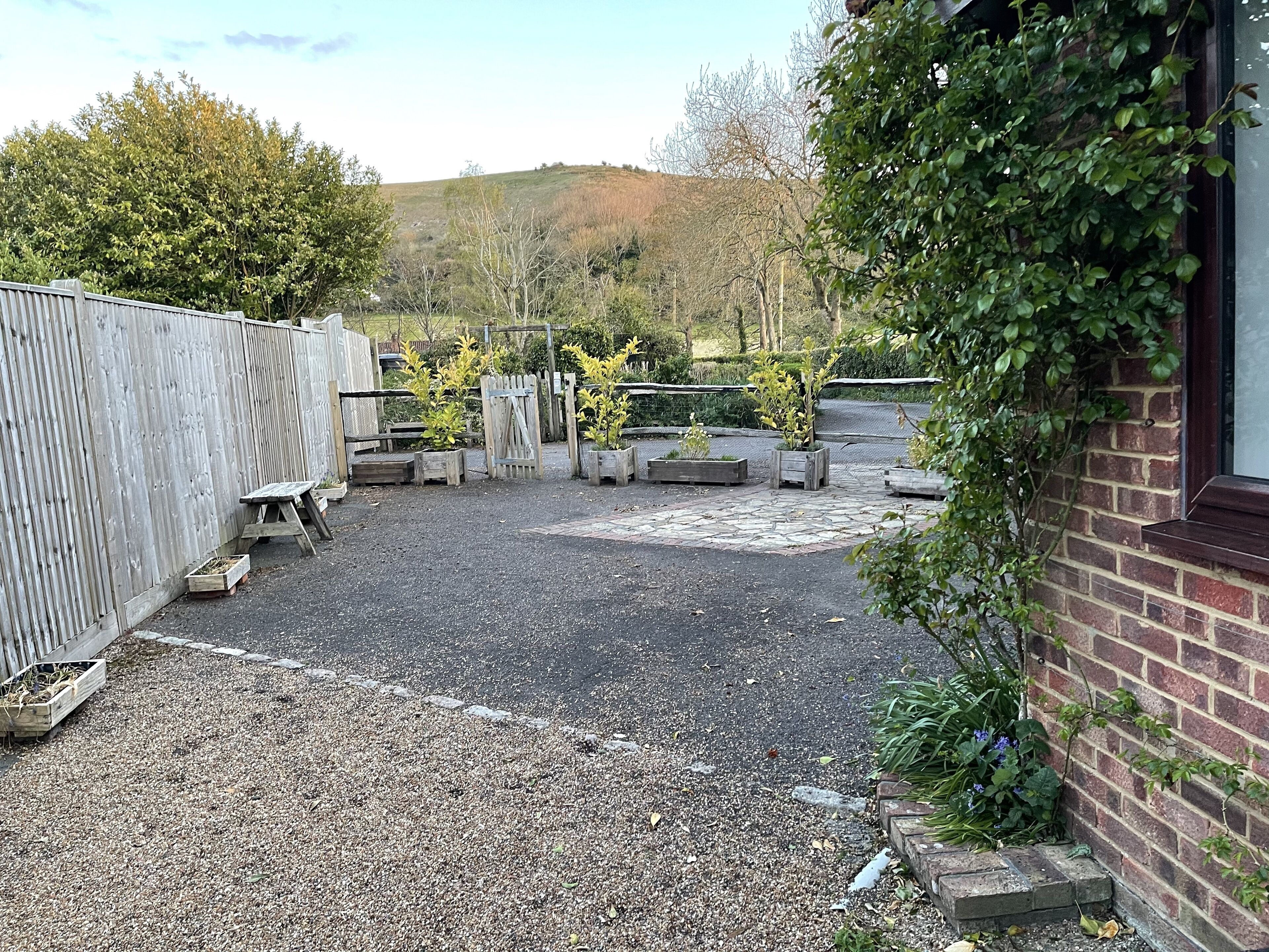 A gravel courtyard with planters and a wooden fence.