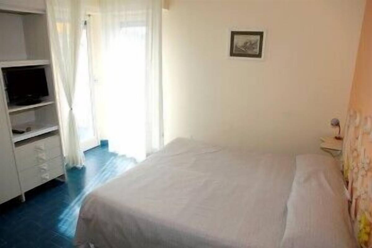 A bedroom with a bed, a TV, a desk, and a chair.