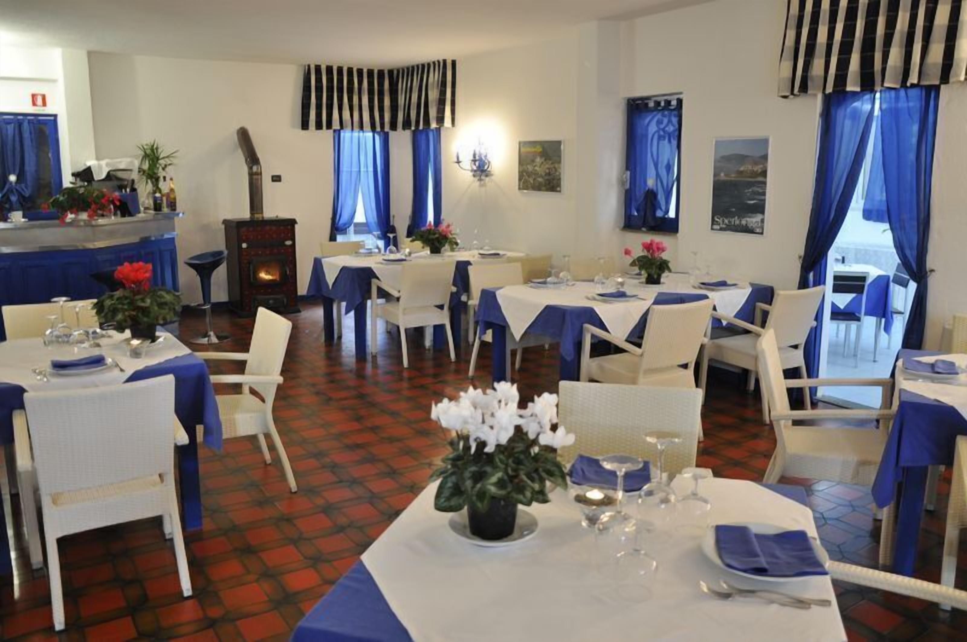A dining area with tables set for service, a fireplace, and blue curtains.