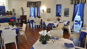 A dining area with tables set for service, a fireplace, and blue curtains.