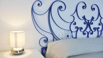 Una cama con cabecera decorativa, una lámpara de noche y una mesita.
