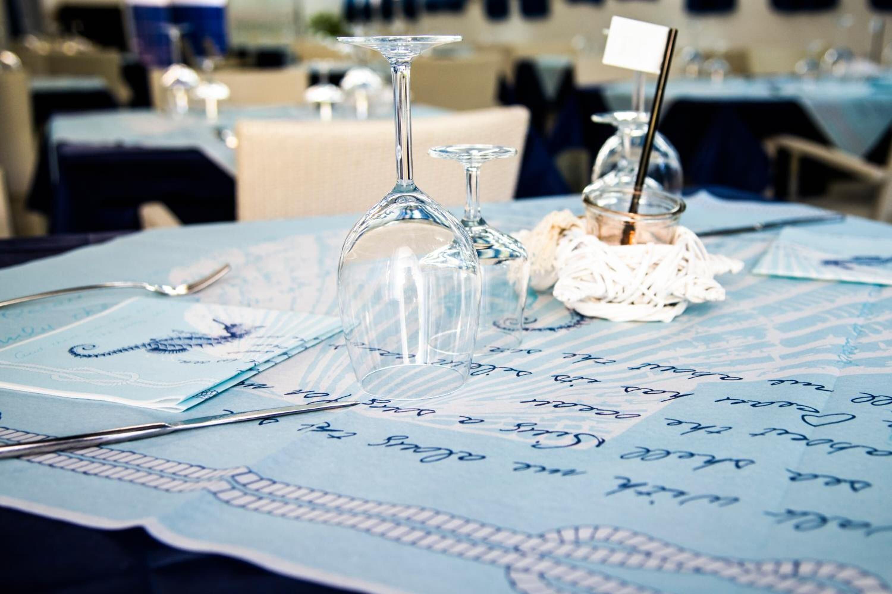 A table set with wine glasses, a spoon, and a small jar with a label.