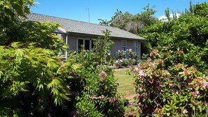 A house with a tiled roof, surrounded by lush greenery and flowering plants. - Edgewater Motel Te Anau (Te Anau)