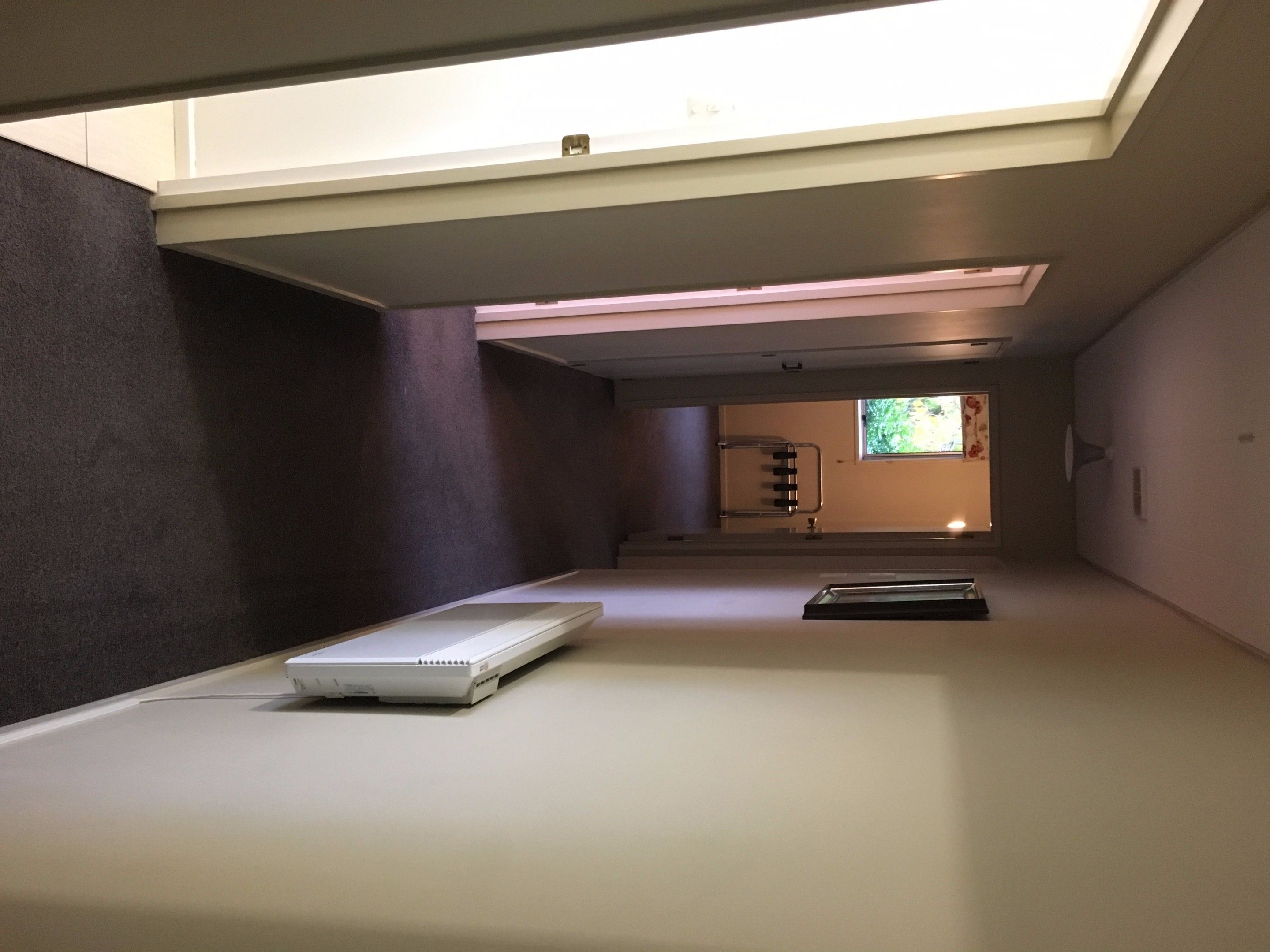 Una habitación de hotel moderna con tragaluz, una cama, un escritorio y vistas al exterior.