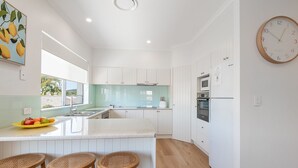 Cocina moderna con armarios blancos, una isla central con taburetes, un microondas y un horno.