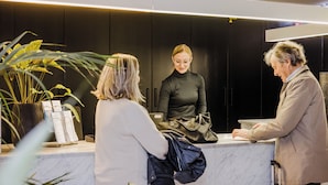 A reception area with a marble counter, potted plants, and a modern interior design.