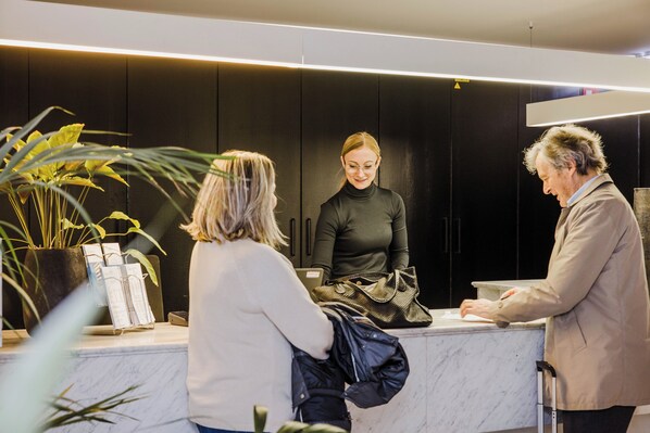 A reception area with a marble counter, potted plants, and a modern interior design. - Corbie Mol (Mol)