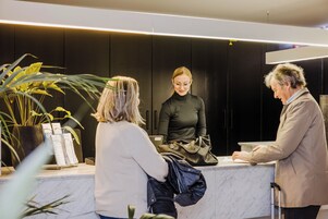 Una zona de recepción con mostrador de mármol, plantas en macetas y un diseño interior moderno.