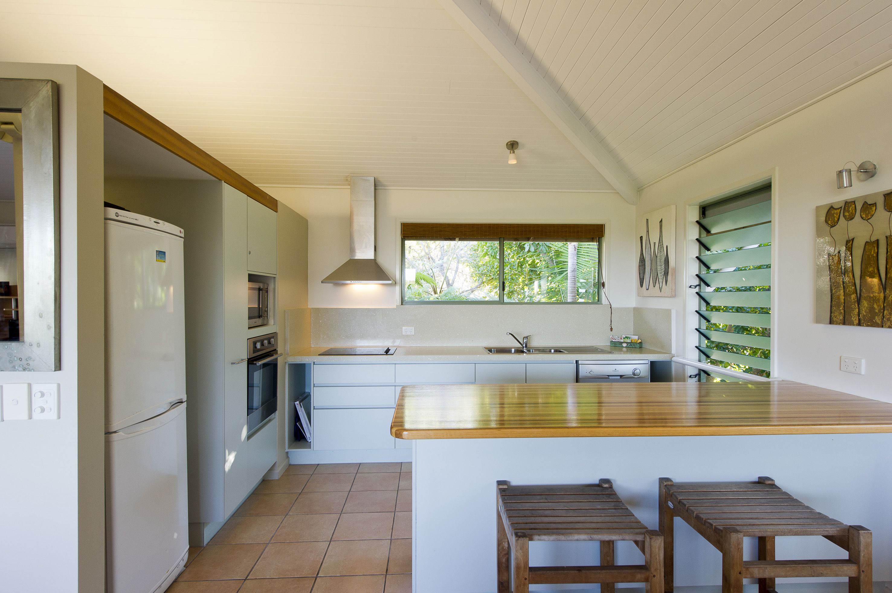 A modern kitchen with a central island, built-in oven, and a large window providing natural light.