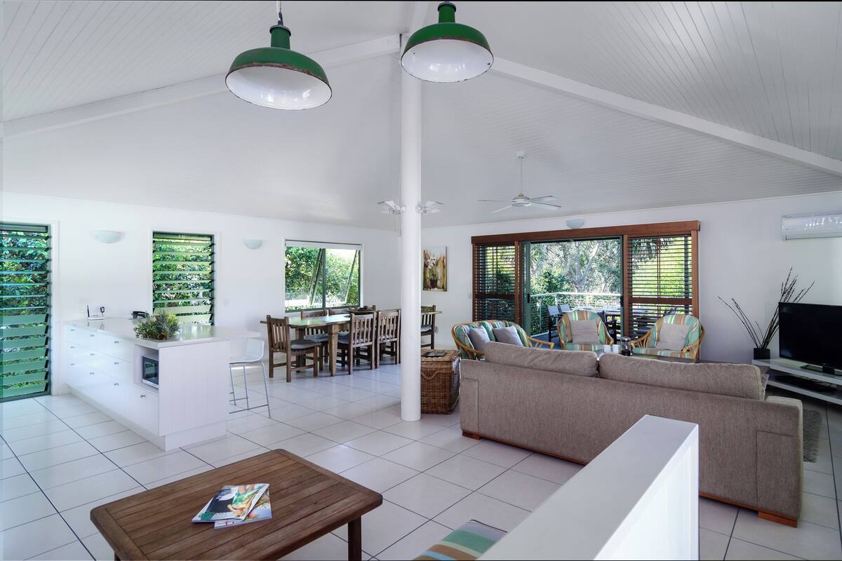A spacious living area with a sofa, a coffee table, and a dining area with chairs and a table.