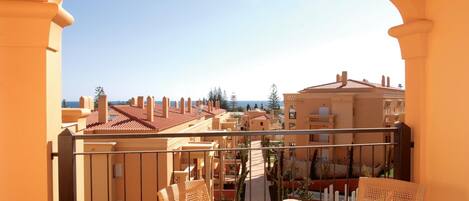 A balcony with a table set for breakfast, overlooking a coastal town.