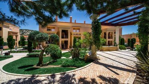 A courtyard with a paved walkway, neatly trimmed hedges, and a building with a central entrance and columns. - Baia da Luz (Lagos)