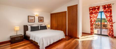 A bedroom with a bed, bedside tables, a wardrobe, and a balcony with curtains.