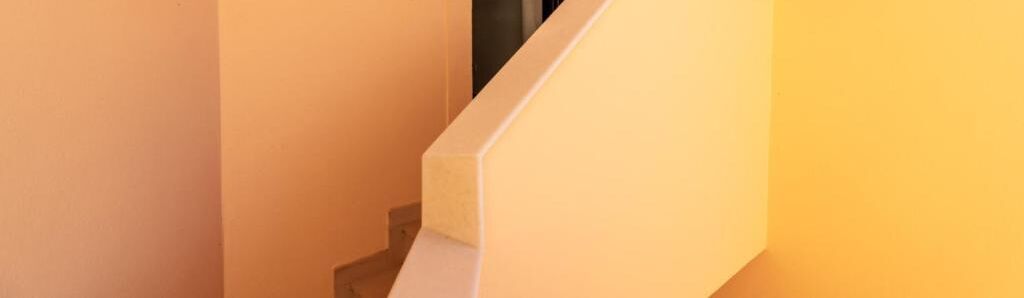 A corner of a room with a white wall and a beige wall meeting at a right angle.