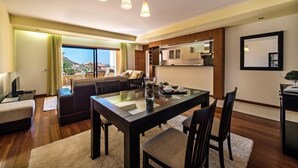 A modern living room with a glass dining table, dark sofas, and a view of the outdoors. - Baia da Luz (Lagos)