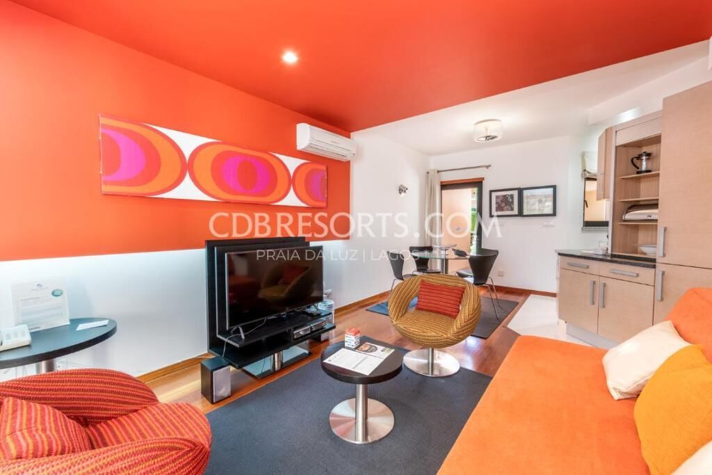 Un salon moderne avec un téléviseur à écran plat, un canapé, un fauteuil et une petite table.