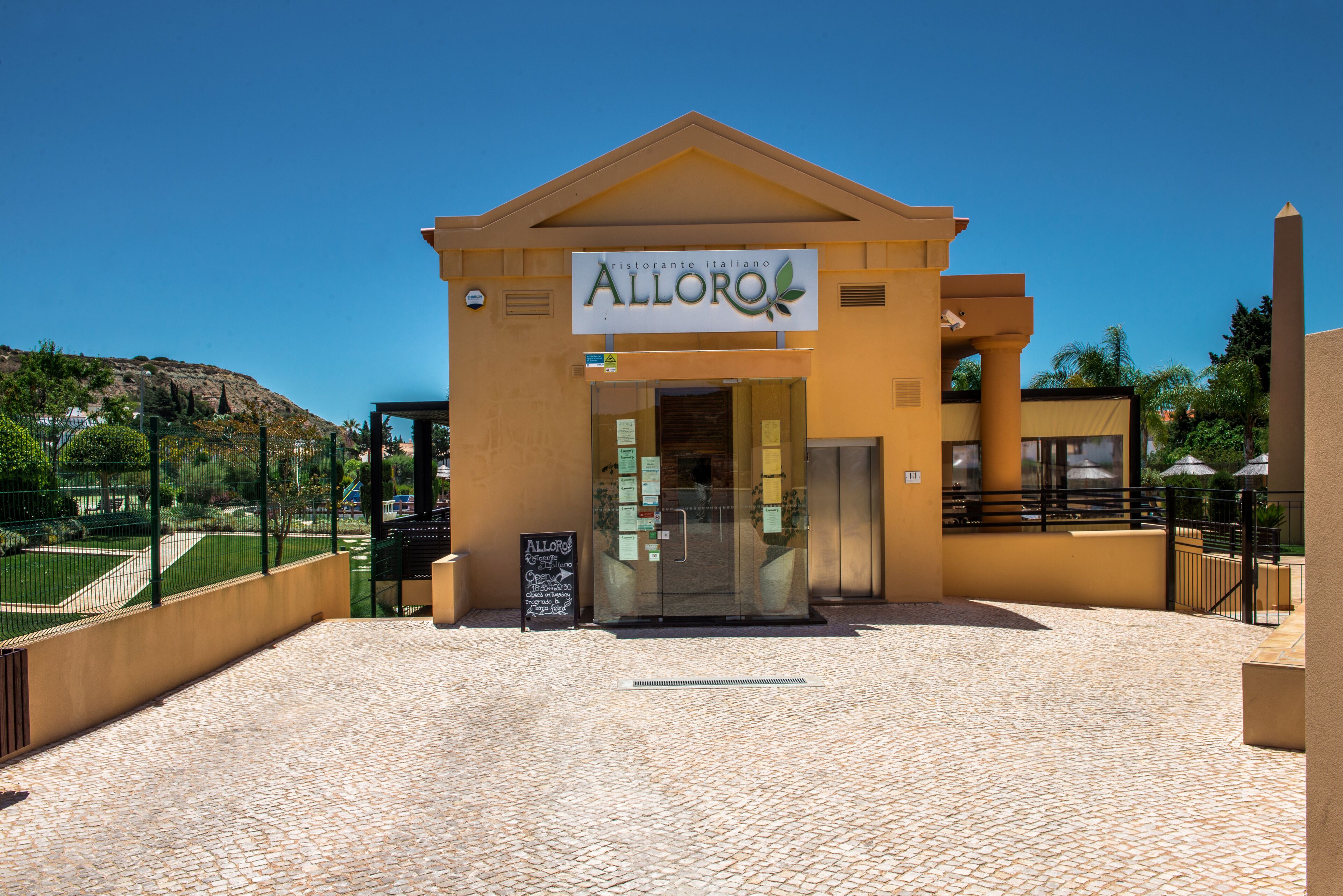 A building with a sign reading "ristorante italiano Alloro" and a chalkboard with writing.