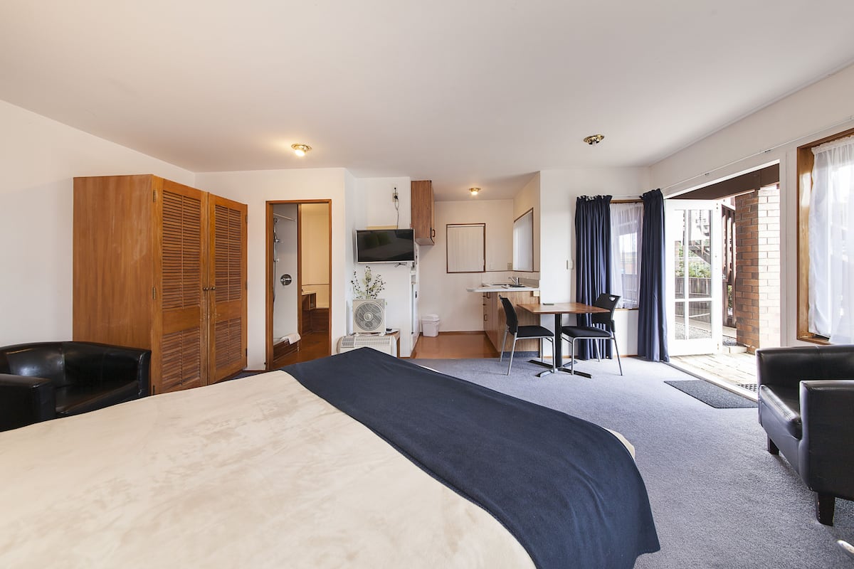 Une chambre d’hôtel avec un lit, un bureau, une chaise et une armoire.