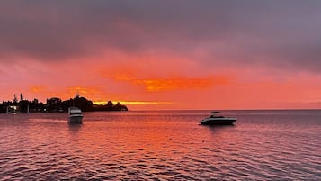 Un atardecer sobre un mar tranquilo con dos barcos.