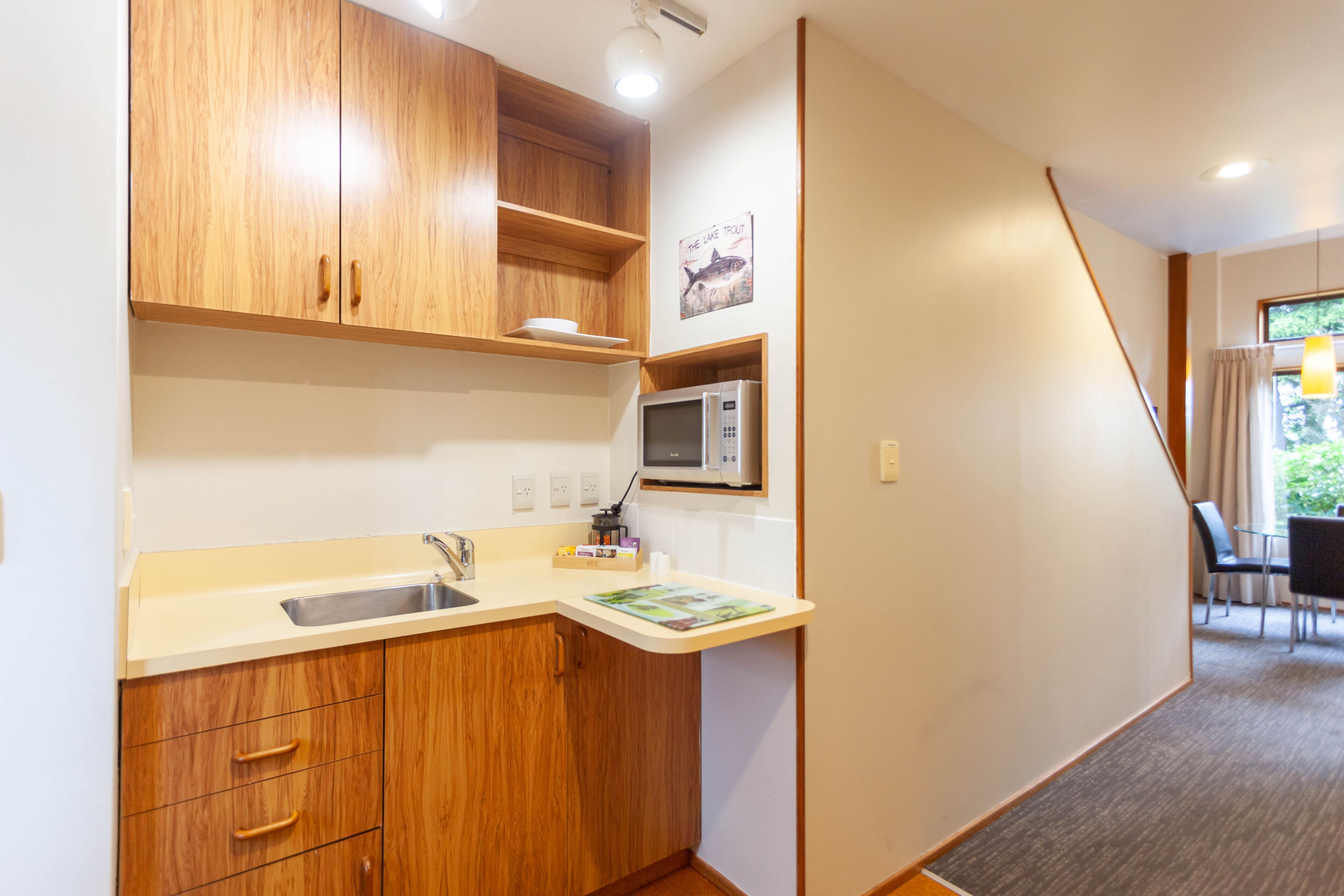 A compact kitchen with wooden cabinets, a microwave, and a sink.