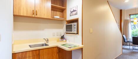A compact kitchen with wooden cabinets, a microwave, and a sink.