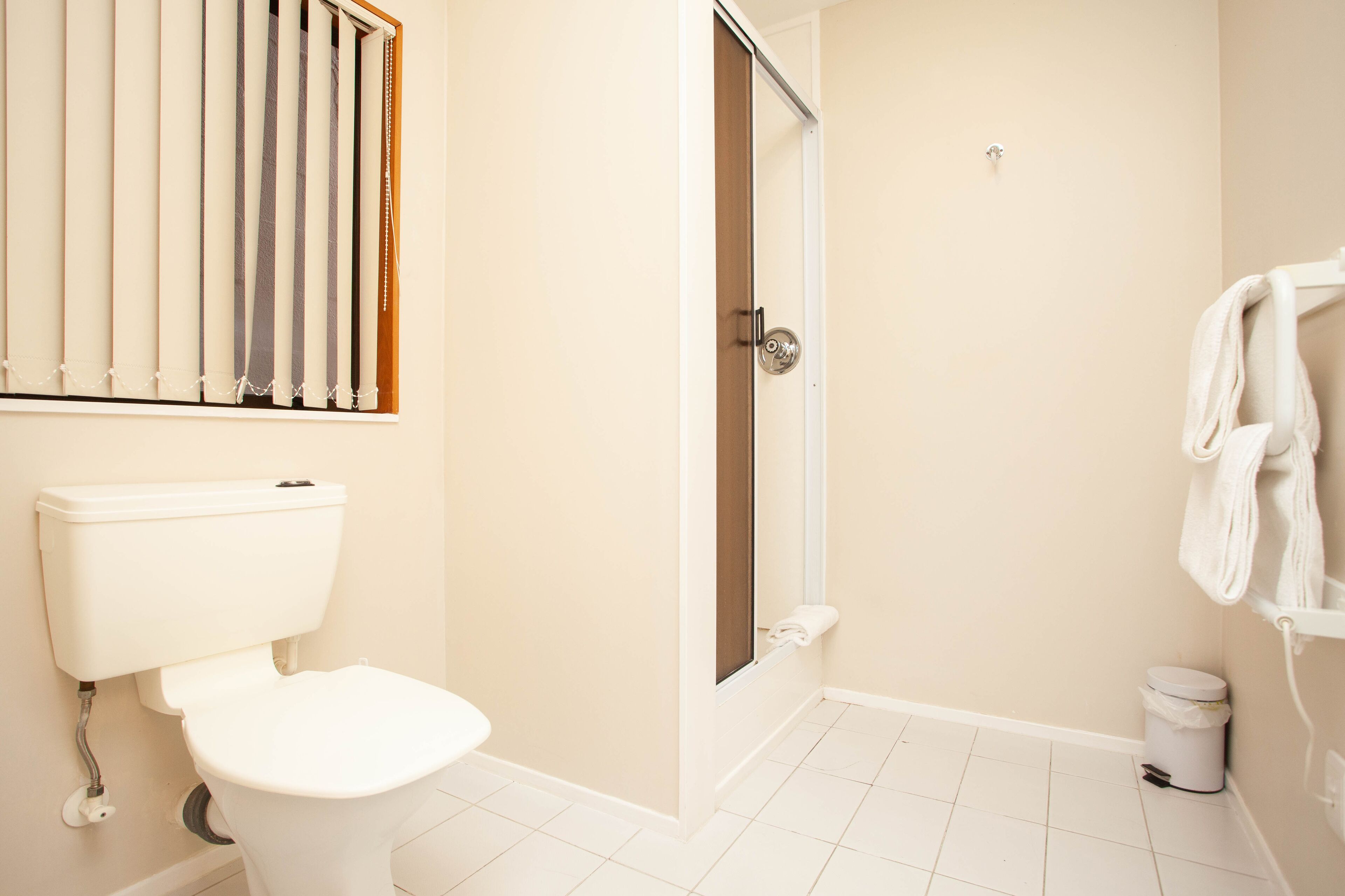 Une salle de bain équipée de toilettes, d’une douche et d’un porte-serviettes.